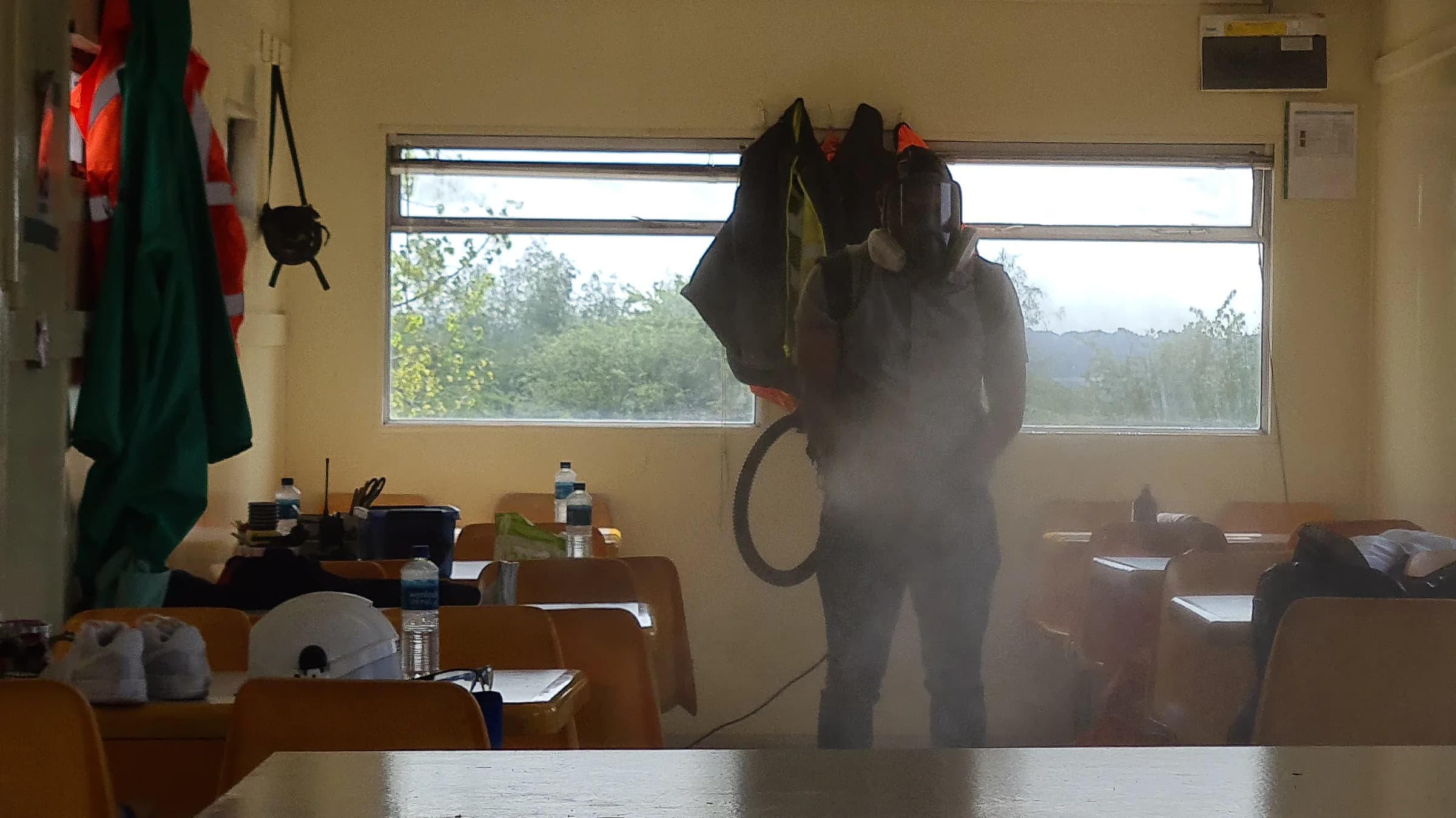 Operative in full PPE and respirator fogging a room during decontamination