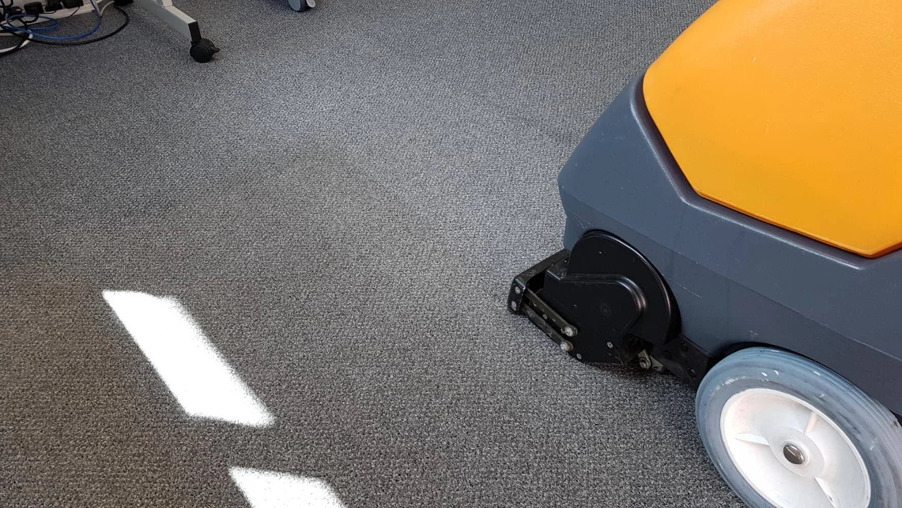 Industrial floor-scrubbing machine cleaning commercial carpet