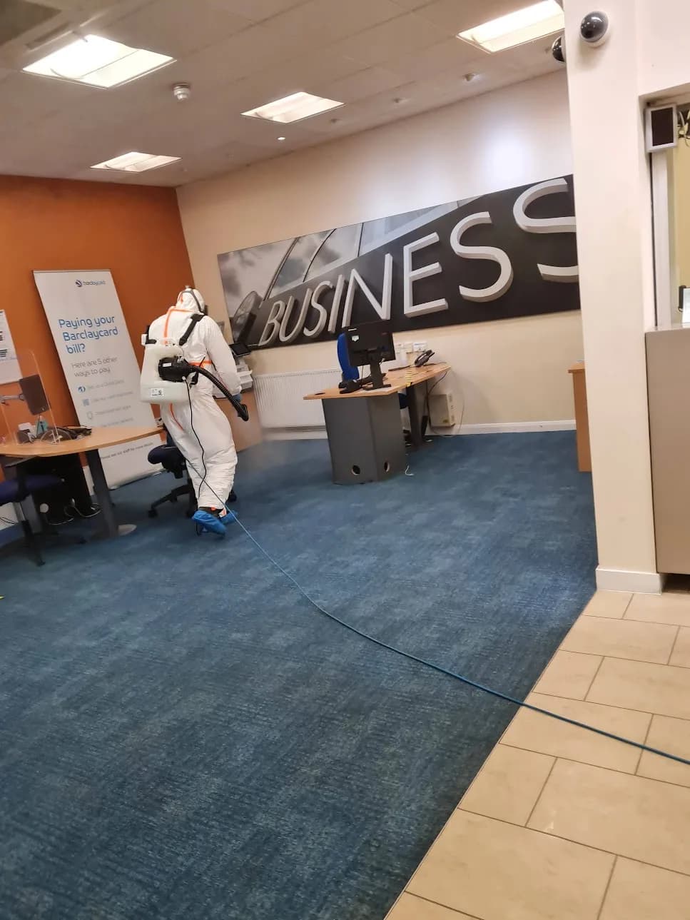 Operative in PPE fog-sanitising a commercial office area