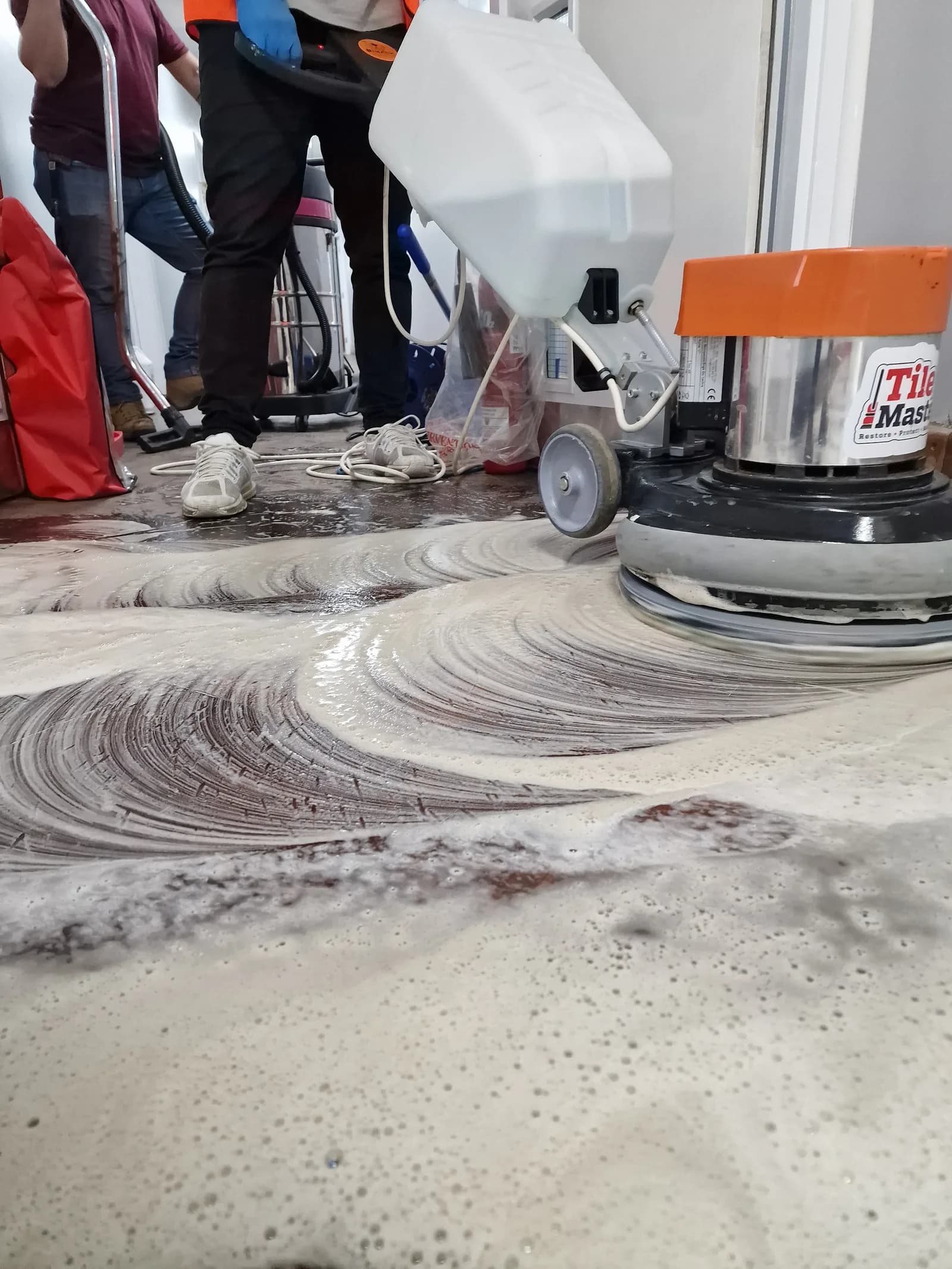 Rotary floor machine scrubbing and restoring a hard floor